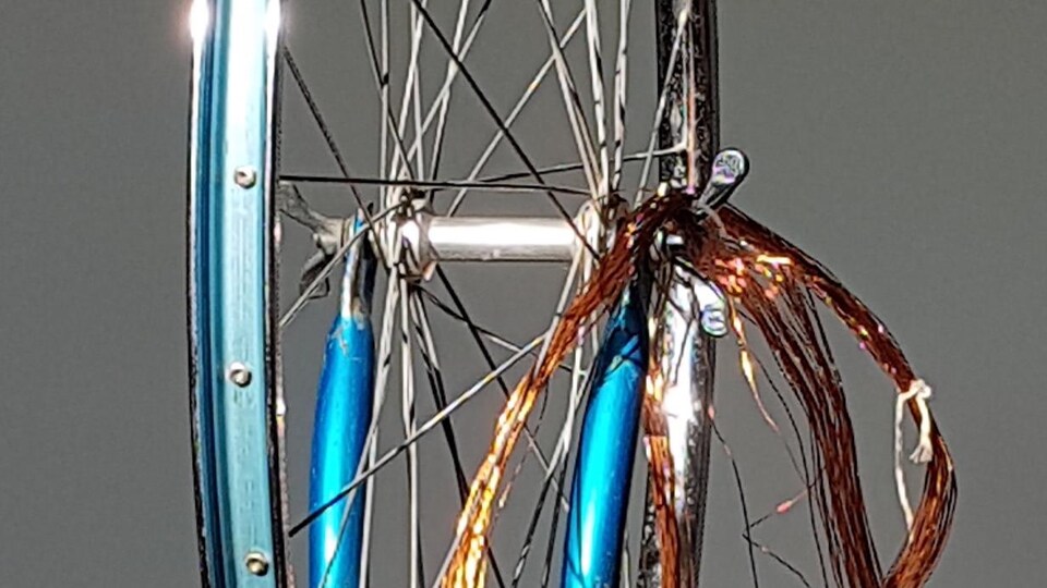 Une roue de bicyclette ornée de fils cuivrés.