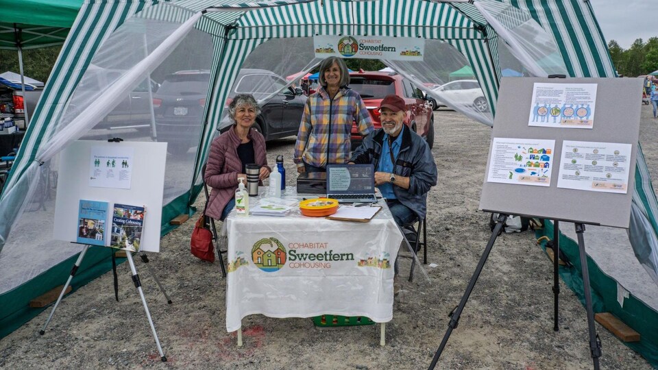 Joanne, Monique et Jean autour d'une table au marché.