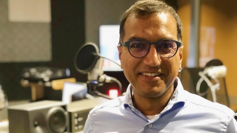 Docteur Andrea Kumar est debout, souriant, avec une chemise bleu pâle, dans le studio de Radio-Canada à Sudbury