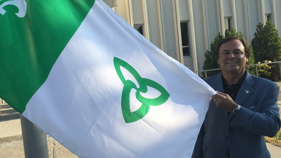 Donald Obonsawin avec le drapeau franco-ontarien à l'Université de Sudbury.