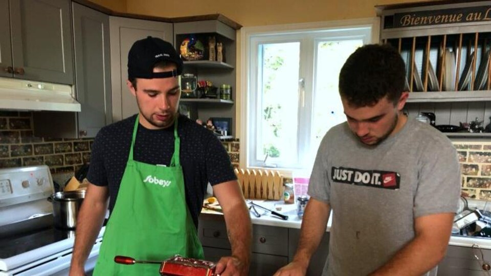 Deux jeunes hommes travaillent dans une cuisine.