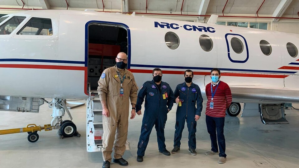 Les quatre hommes debout devant un avion de du CNRC.