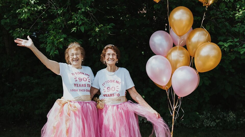 Rolande et Fernande vêtues de tutus roses à côté de ballons gonflables, à l'extérieur.