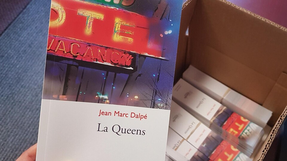 Une main tient une copie de la pièce de théâtre « La Queens » de Jean-Marc Dalpé