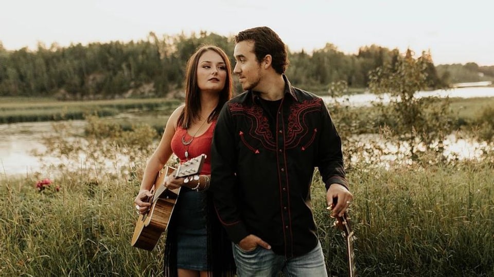 Une jeune femme et un jeune homme en pleine nature avec leurs guitares