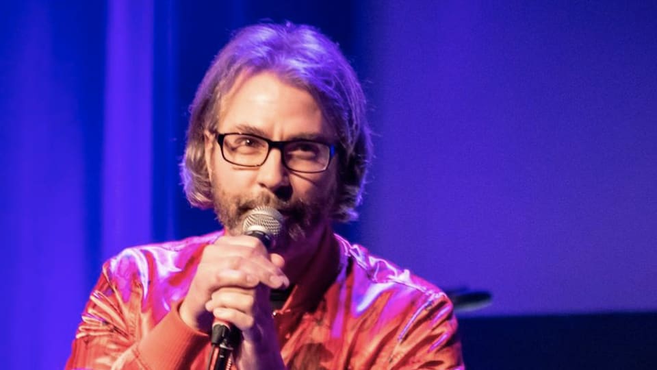Un chanteur tient un microphone avec deux mains.