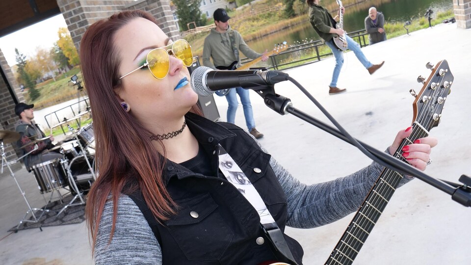 Une jeune femme joue à la guitare près d’une scène en plein air