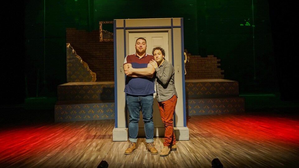 Deux hommes debout devant un cadre de porte dans un décor de théâtre