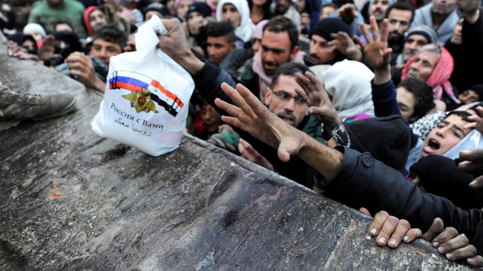 Des civils d'Alep-Est, en Syrie, tentent d'attraper des sacs lors d'une distribution d'aide humanitaire.