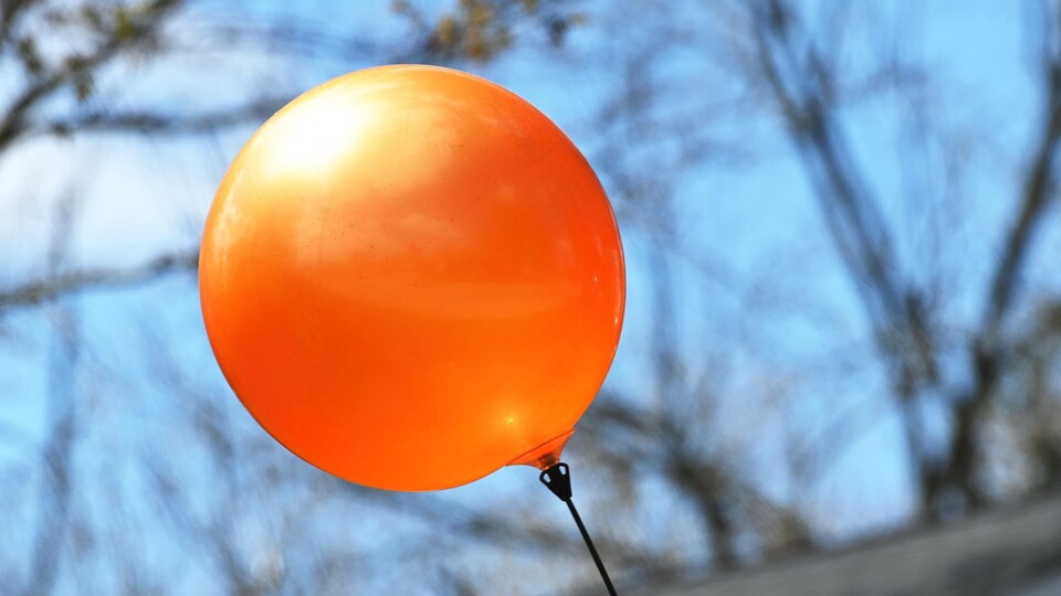 Un ballon de plastique orange flotte dans les airs.