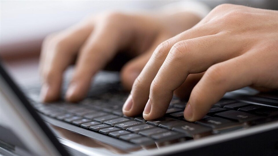 Une personne pose ses mains sur un clavier d'ordinateur.