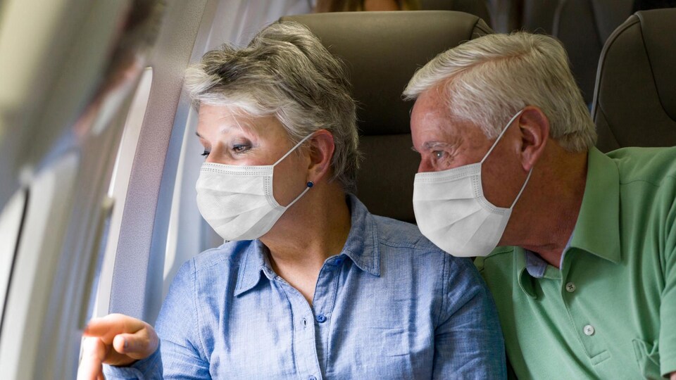 Une femme et un homme âgés sont assis dans un avion.