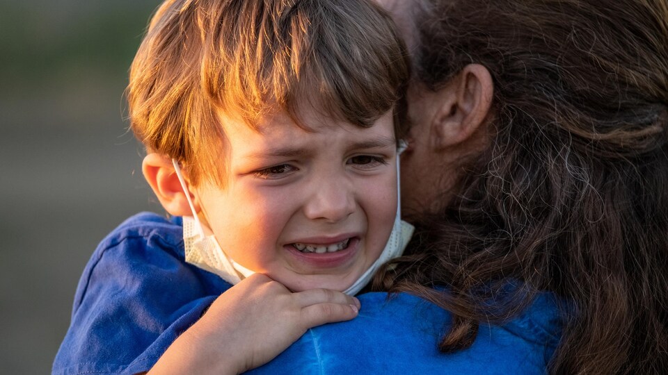 Un enfant pleure dans les bras de sa mère.