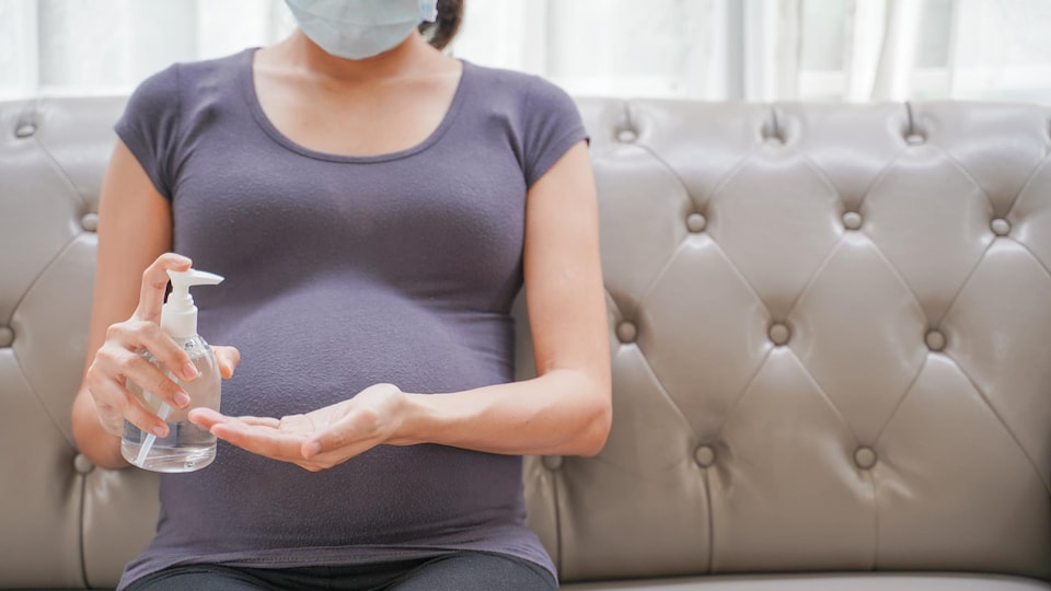 Une femme enceinte se nettoie les mains pour se protéger de la COVID-19.