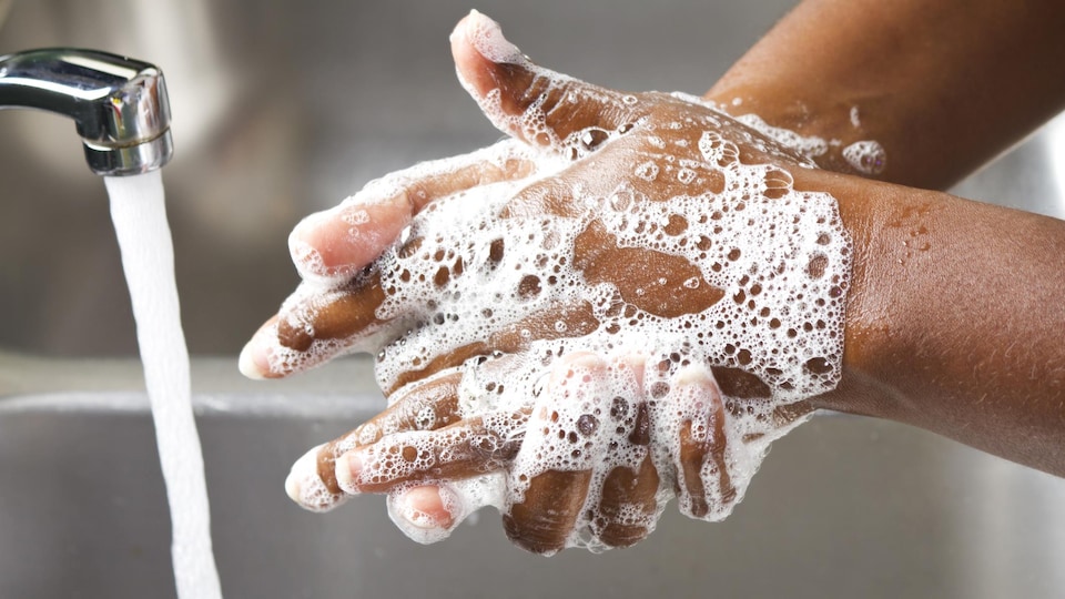 Une personne se lave les mains avec du savon dans un évier.