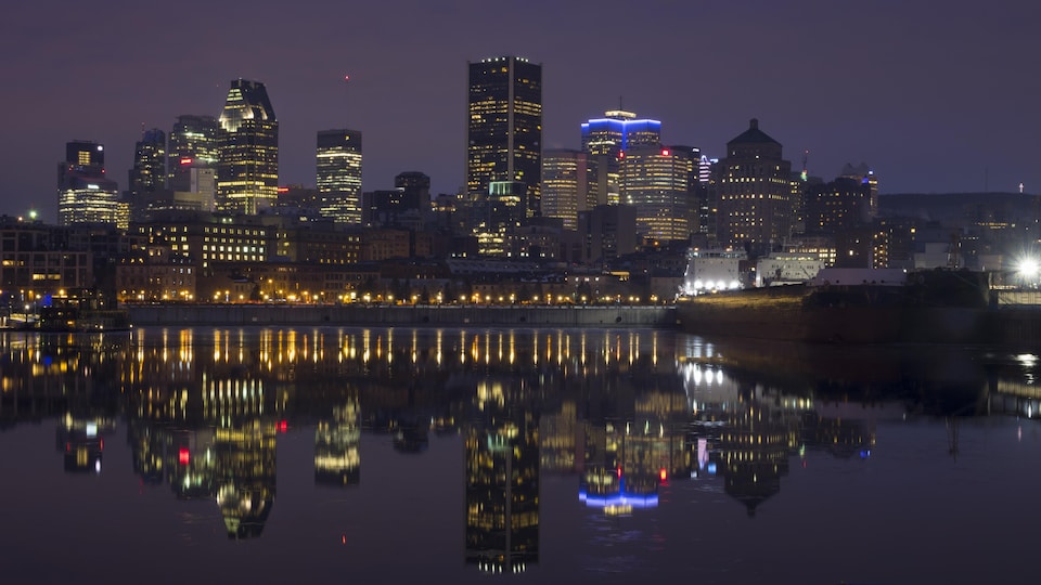 Les édifices de la ville de Montréal se reflètent dans les eaux du Vieux-Port à l'aube d'une journée de janvier.