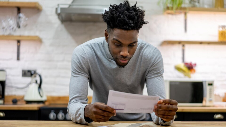 Une personne consulte une facture en papier qu'il vient de recevoir par la poste.