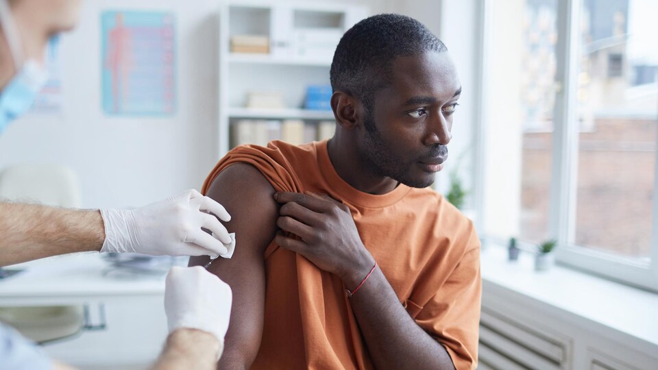 Une personne se fait vacciner sur le bras droit.