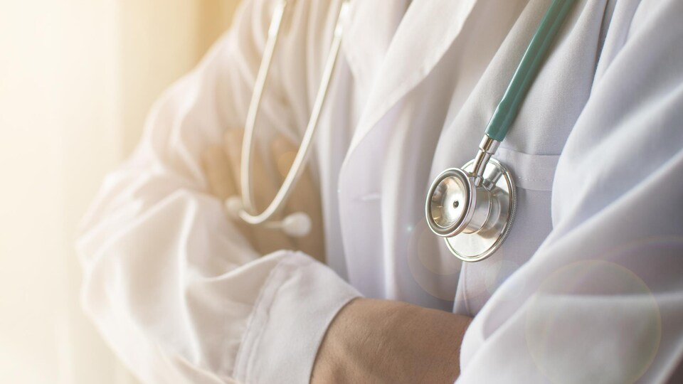 Un médecin portant un stéthoscope se croise les bras.