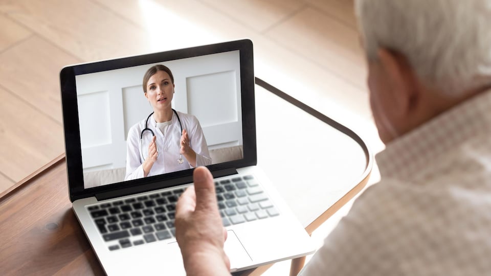 Un homme âgé consulte un médecin sur son ordinateur.