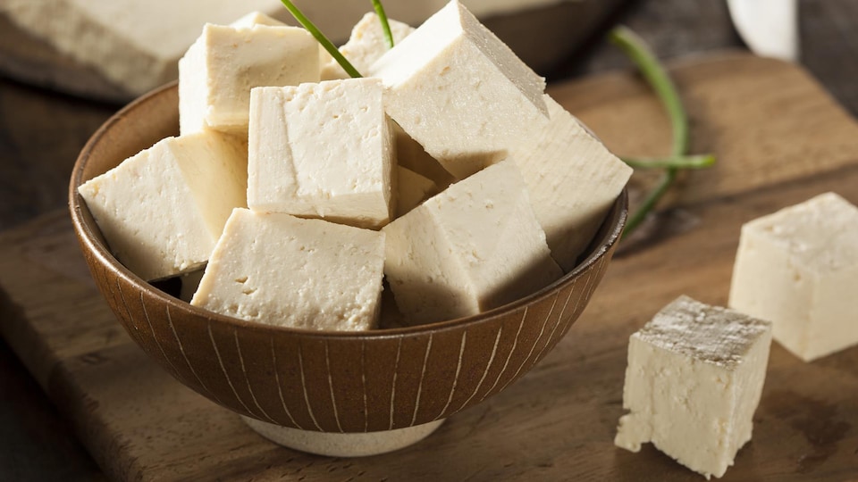 Des cubes de tofu sont disposés dans un bol qui repose sur une table.