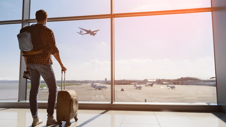 Un homme attend son vol dans un aéroport.