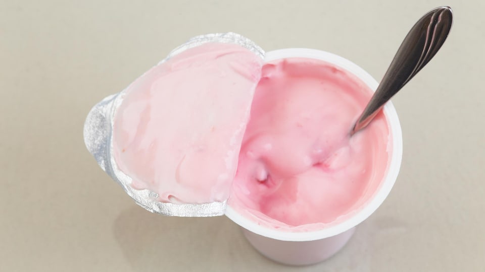 Une cuillère déposée dans un contenant de yogourt.
