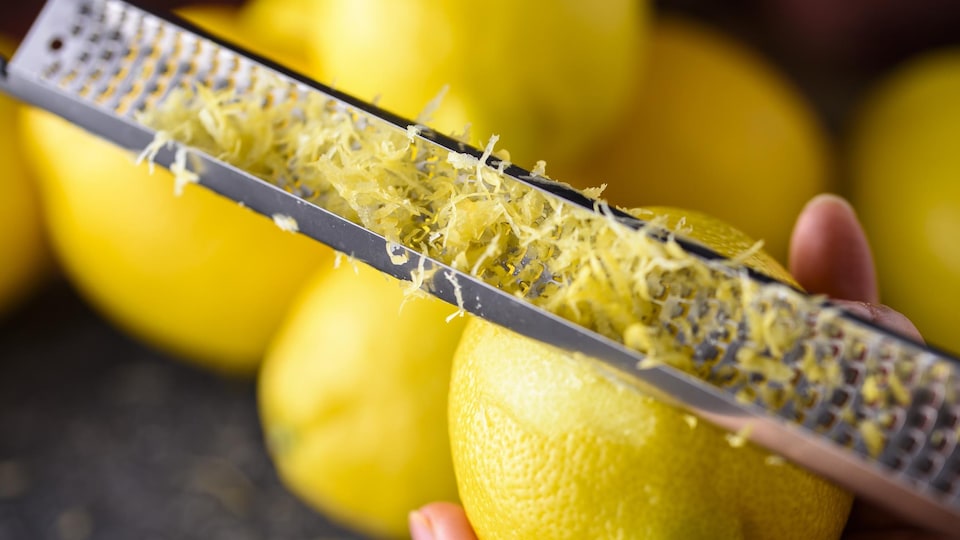 Une personne râpe un citron pour obtenir du zeste.