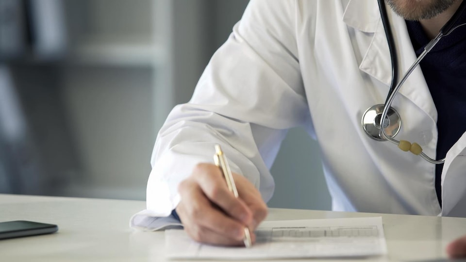 Un médecin écrit sur un papier.