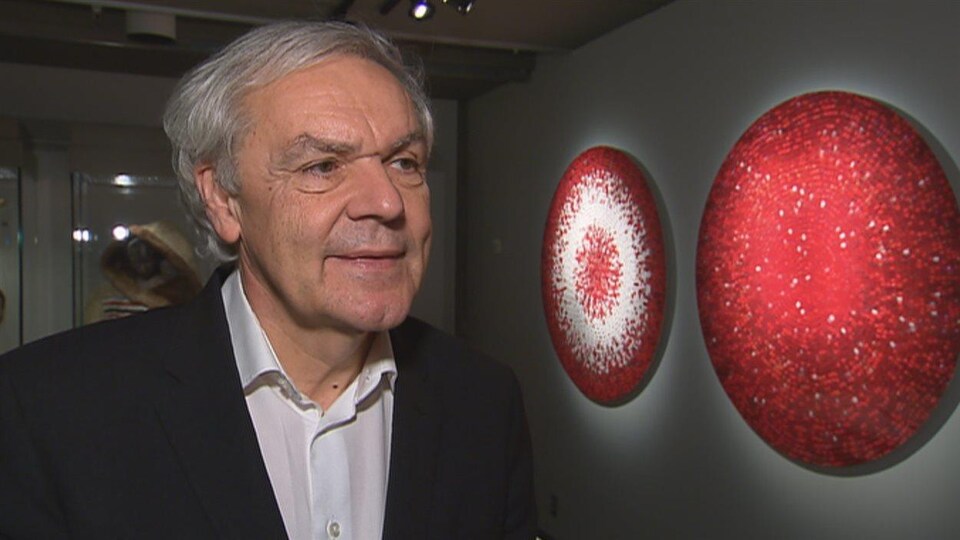 Le muséologue Michel Côté se trouve dans une pièce contenant une oeuvre d'art.