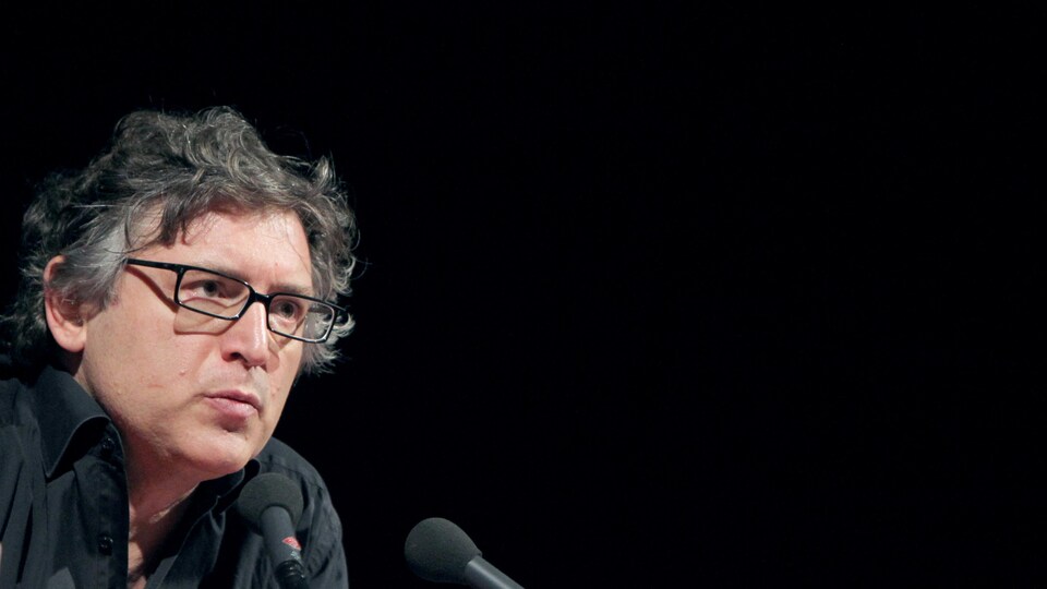 Il parle devant un micro.