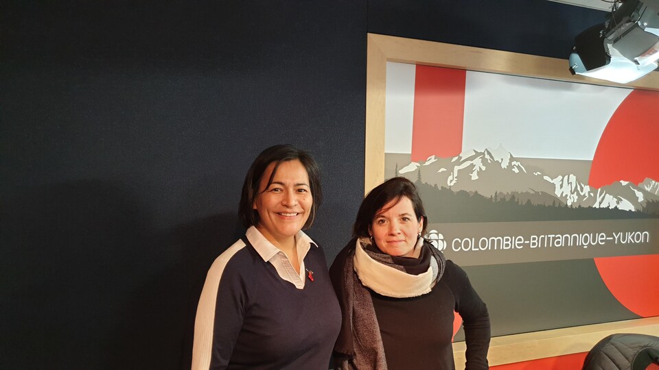 Deux femmes sont photographiées plan taille dans un studio de radio.