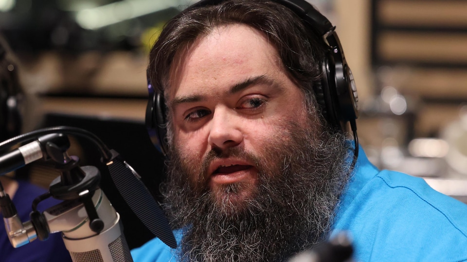 L'auteur et chroniqueur Mickaël Bergeron devant un micro dans un studio de radio.
