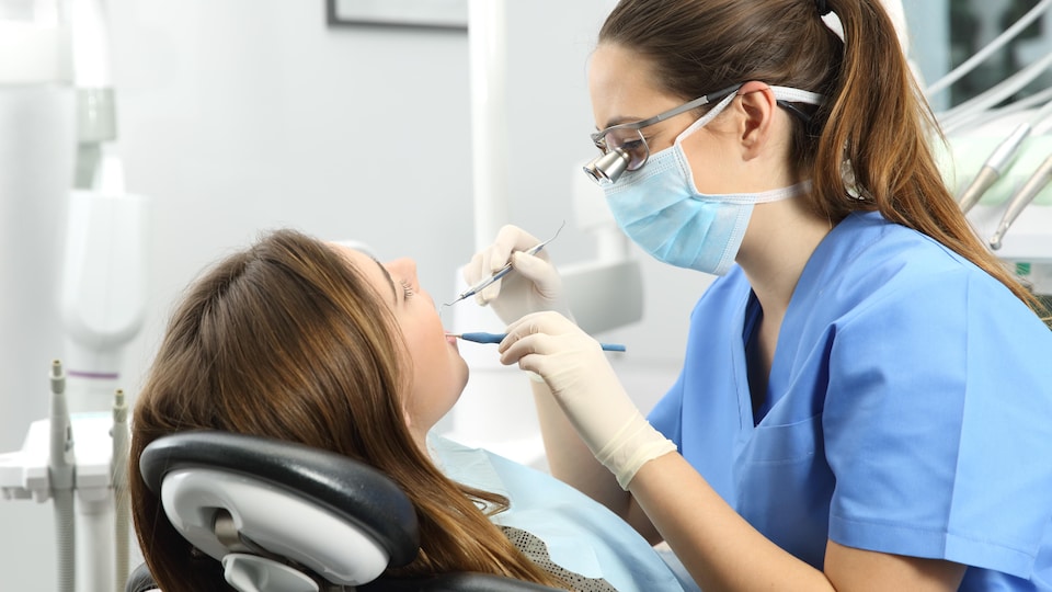 Une hygiéniste dentaire fait l'évaluation d'une patiente. 