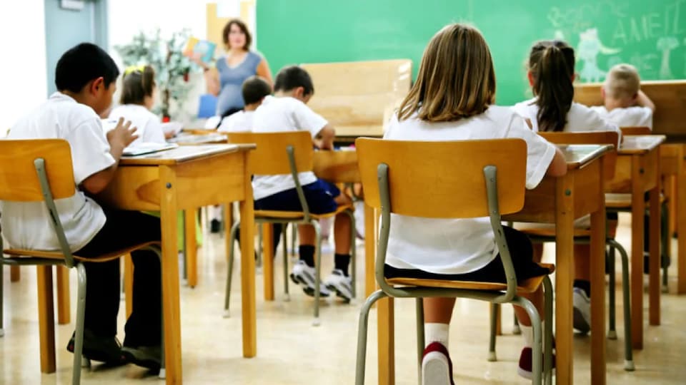 Une salle de classe avec des enfants de dos.