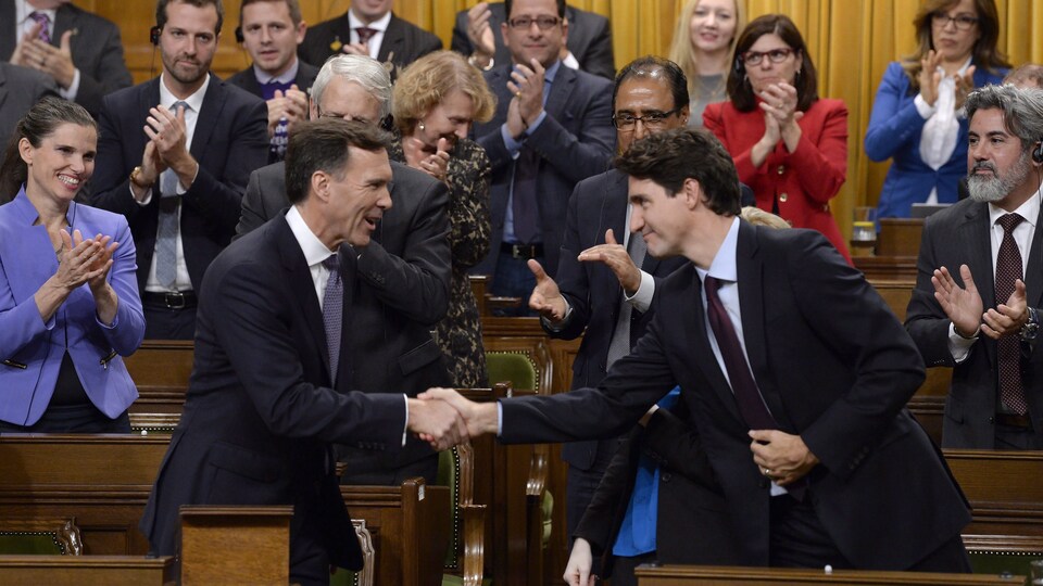 Bill Morneau et Justin Trudeau se serrent la main à la Chambre des communes.