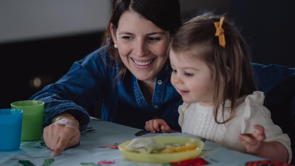 Une mère et une fille et assise à table.