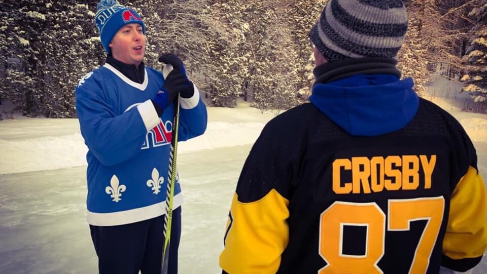 Deux joueurs de hockey discutent sur une patinoire extérieure