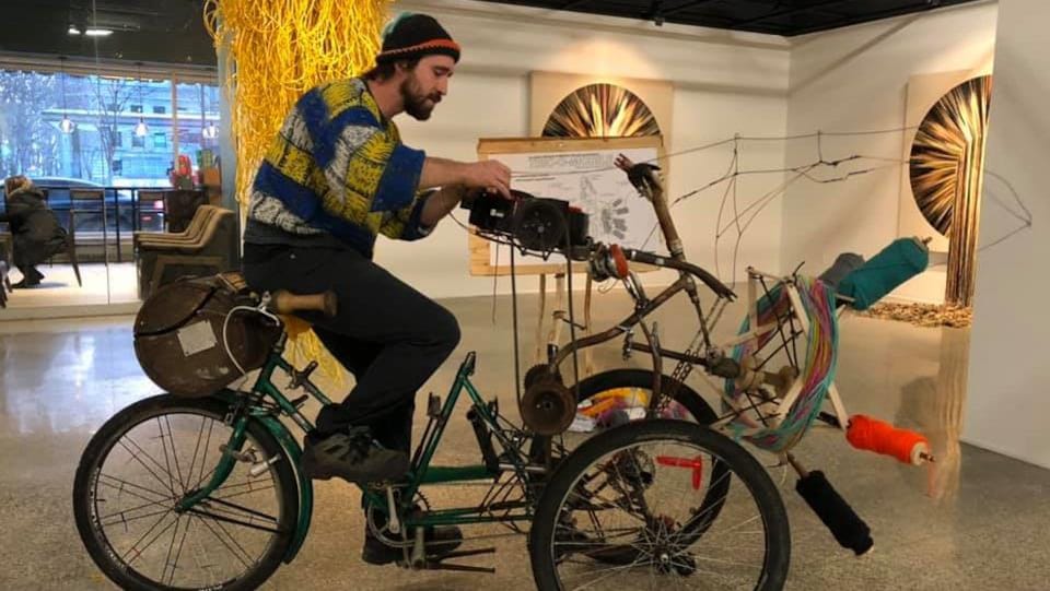 L’artiste Mathieu Fecteau sur sa sculpture machine à tricoter, fabriquée à partir de pièces de vieux vélos