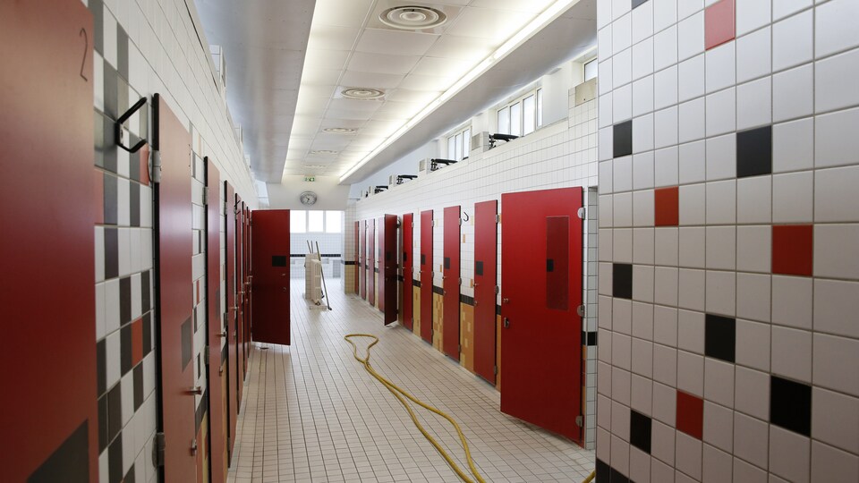 Vue d'un corridor avec portes de cabinets de douche au bain public de la rue des Haies, à Paris.