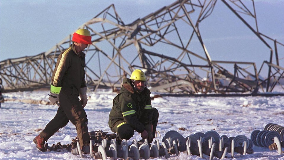 Deux hommes réparent un pylône détruit, en janvier 1998