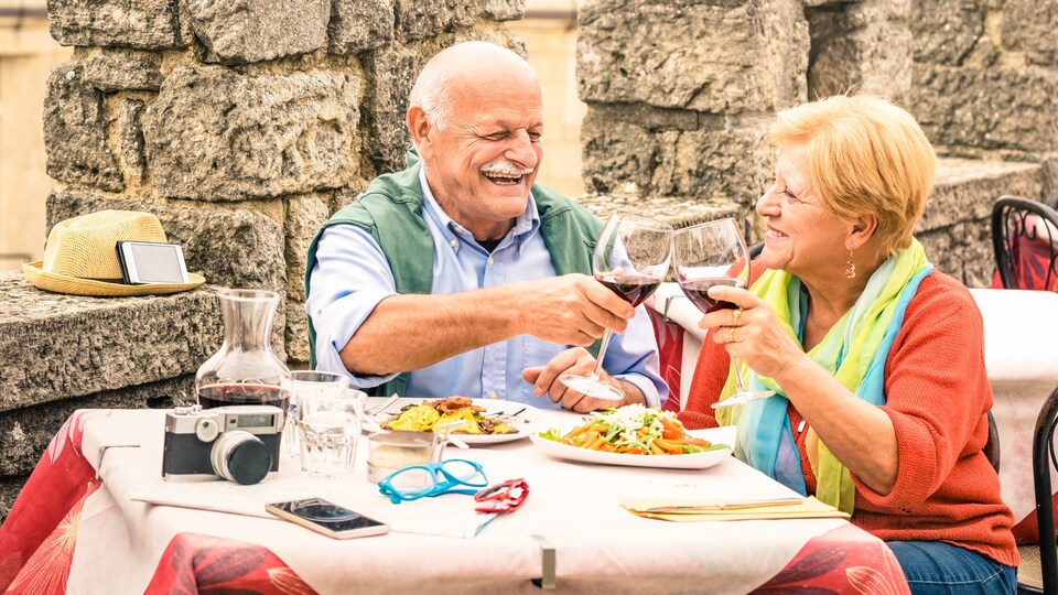 Un couple âgé trinque à table durant ses vacances.