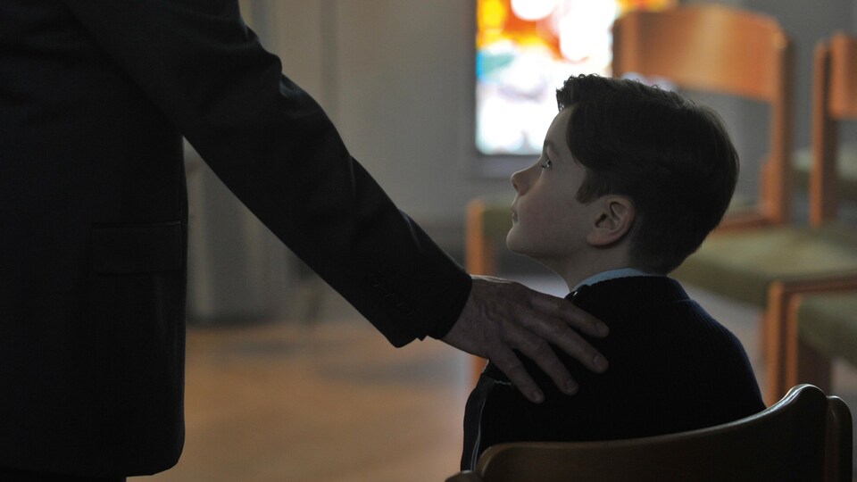 Un homme met pose sa main sur l'épaule d'un jeune garçon dans cette image du film Grâce à Dieu, de François Ozon.