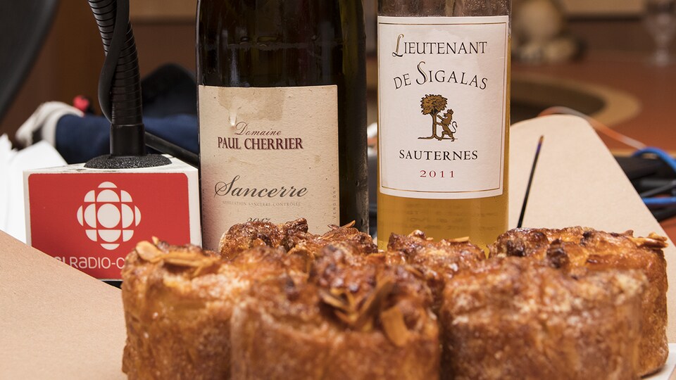 Gros plan sur les bouteilles sélectionnées par Élyse Lambert et sur des gâteaux kouign-amann aux pêches.