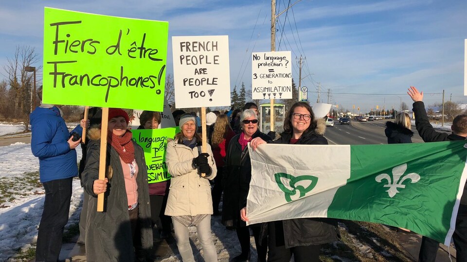 Des manifestants avec des enseignes et un drapeau franco-ontarien à Cambridge, en Ontario.