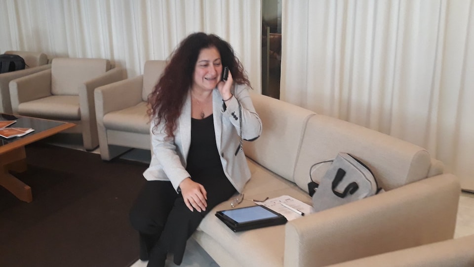 Maria Mourani au téléphone, assise sur un divan.