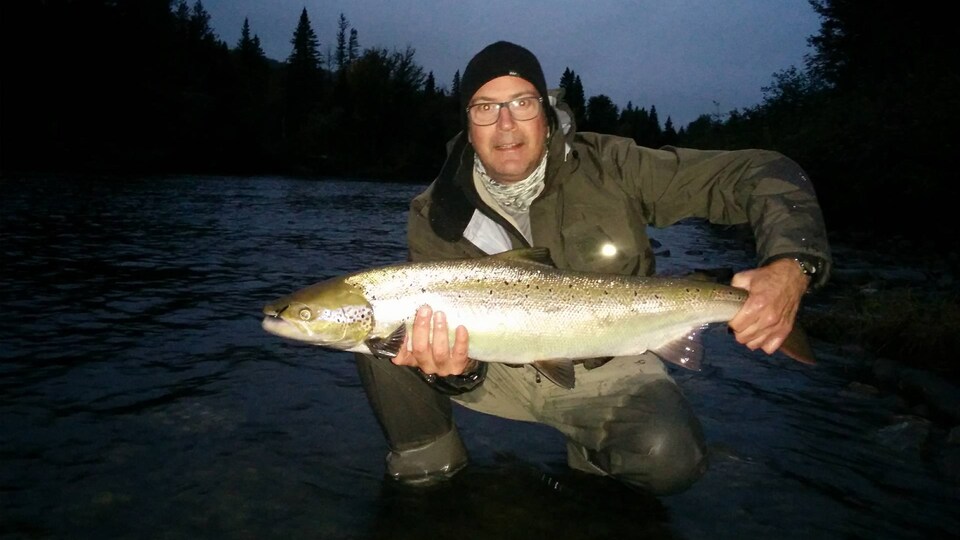 Notre technicien, Pierre Plante, tient un imposant saumon qu'il a lui-même pêché.