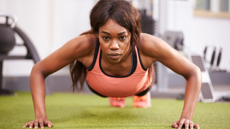 Une femme fait des pompes dans une salle d'entraînement physique.