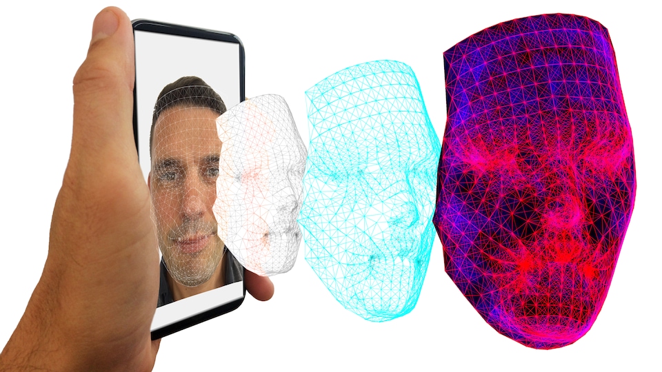 Un homme tient un téléphone montrant son visage, qui est numérisé par un logiciel de reconnaissance faciale.