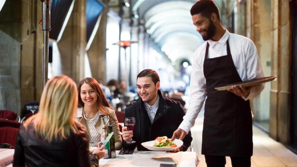 Un serveur avec ses clients dans un restaurant